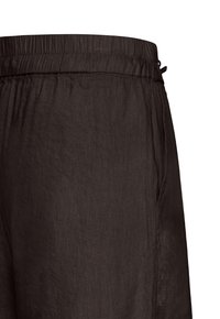 Gros plan sur un pantalon à taille élastique brun foncé avec une poche latérale visible et un tissu texturé.