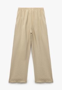 Pantaloni beige a gamba larga con vita elasticizzata, tessuto testurizzato e vestibilità ampia. Nessuna tasca o dettagli hardware visibili.