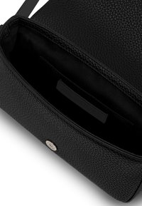 Borsa a tracolla in pelle nera texturizzata con un interno aperto, dotata di fodera in satin, una piccola tasca e un logo metallico accentuato vicino al fondo.