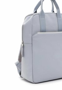 Grå ryggsäck i slätt material med dubbla topphandtag, en framficka med dragkedja och justerbara vadderade axelremmar.