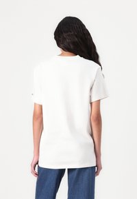 White cotton t-shirt with a relaxed fit, short sleeves, and crew neck. The back is plain with no graphics or embellishments.
