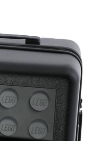 Svart plastfodral med fyra runda, texturerade LEGO-prydnader på framsidan, dragkedjeförslutning och ett rejält handtag.