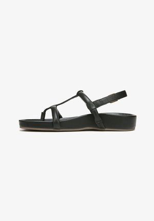 Black leather sandal featuring a T-strap design, cushioned footbed, adjustable back strap, and a flat, solid base.