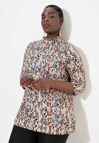 Geprinte blouse met een hoge kraag. Heeft een beige basis met zwarte, rode en blauwe abstracte patronen. Driekwart mouwen en een zachte stofkwaliteit.