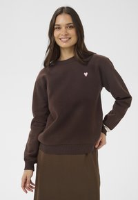 Rjava jopa z okroglim izrezom in dolgimi rokavi, na prsih ima majhen rožnat srčkan logotip. Gladek material in rebrasti manšeti.