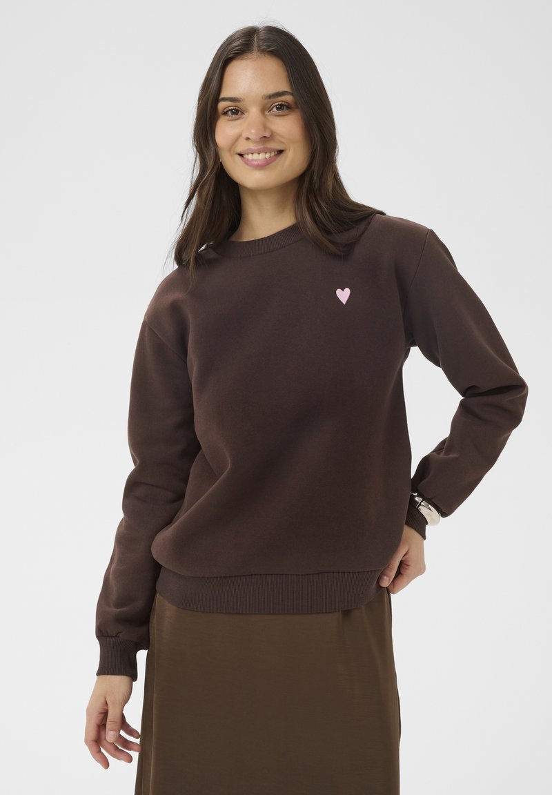 Rjava jopa z okroglim izrezom in dolgimi rokavi, na prsih ima majhen rožnat srčkan logotip. Gladek material in rebrasti manšeti.