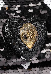 Pochette a forma di cuore con paillettes nere e superficie testurizzata. Presenta una chiusura a forma di gufo in tonalità oro decorata con pietre nere.