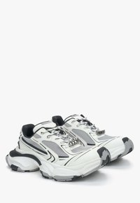 Sportieve schoenen in wit en grijs met gaaspanelen, zwarte accenten, dikke demping en metalen vetersluisjes.