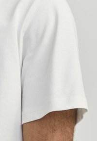 T-shirt bianco a maniche corte con una morbida texture in cotone. Presenta un collo rotondo e bordi cuciti puliti, evidenziando una vestibilità rilassata.