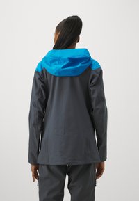 Giacca impermeabile con un corpo grigio scuro, cappuccio blu e accenti sulle maniche. Tessuto liscio con un design aderente e cappuccio regolabile.