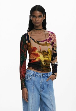Long-sleeve top featuring a multicolored floral and abstract pattern on a soft fabric, paired with light blue high-waisted jeans.