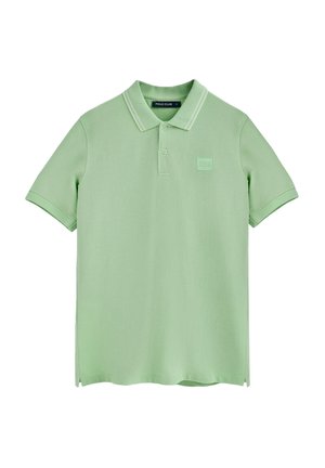 Camisa polo en verde claro, hecha de una tela suave. Cuenta con un cuello clásico, tapeta de tres botones y un parche cuadrado con el logo en el pecho.