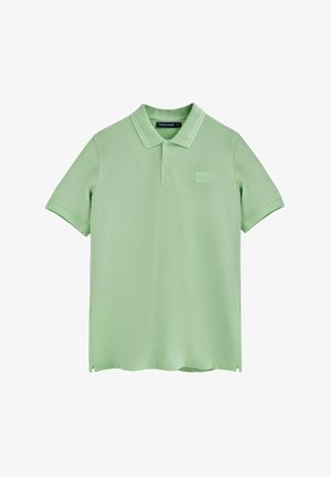 Camisa polo en verde claro, hecha de una tela suave. Cuenta con un cuello clásico, tapeta de tres botones y un parche cuadrado con el logo en el pecho.
