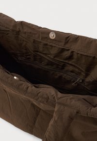 Borsa tote in tessuto marrone con una tasca con cerniera all'interno, caratterizzata da cuciture orizzontali e una chiusura a bottone sul bordo superiore.