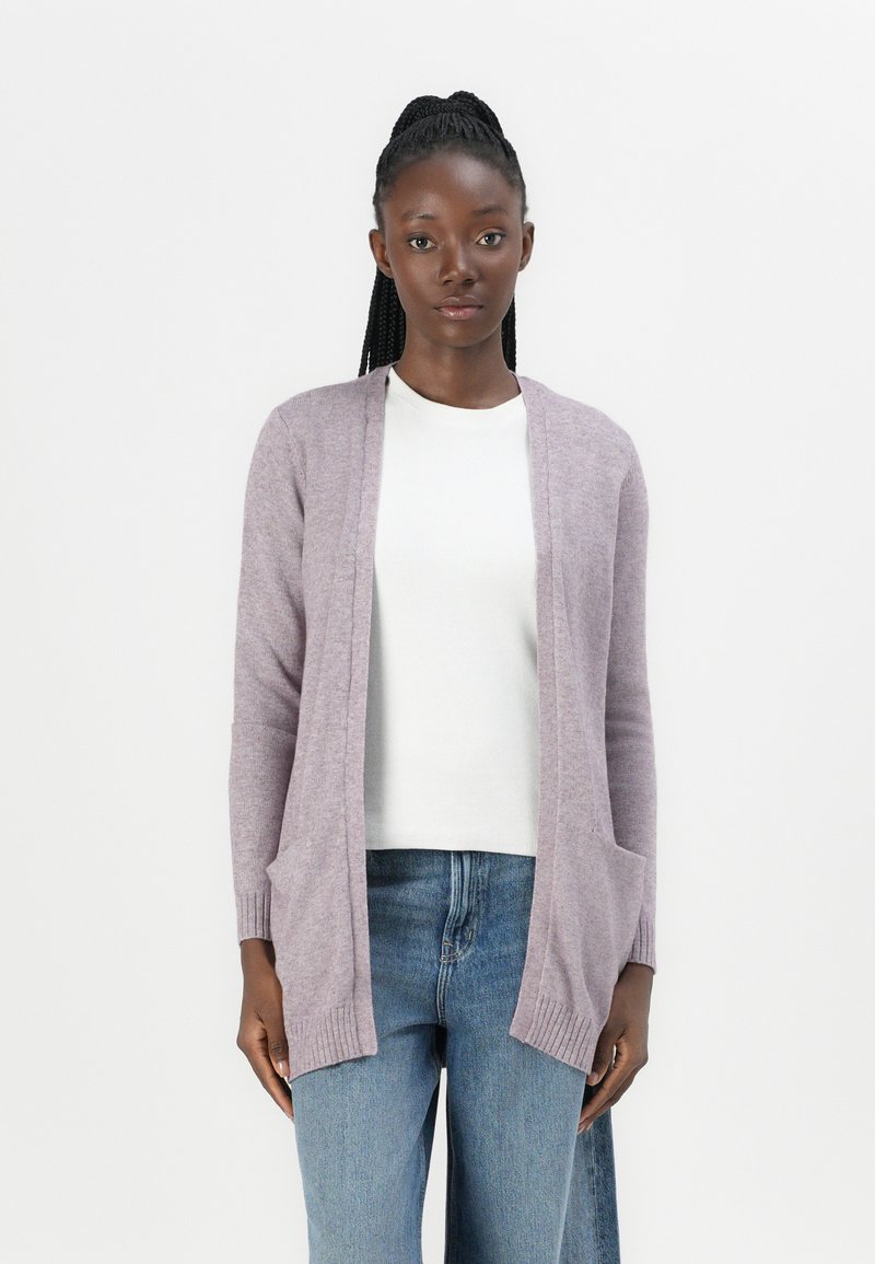 Licht lila cardigan van zachte stof, met een open voorkant, geribbelde manchetten en twee voorzakken. Gemaakt over een witte top.