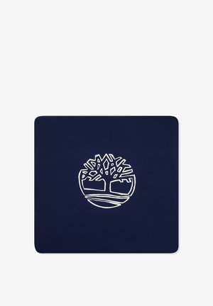 Tapis bleu marine arborant un logo blanc d'un arbre dans un cercle, avec des branches et des racines stylisées. Texture lisse et durable.