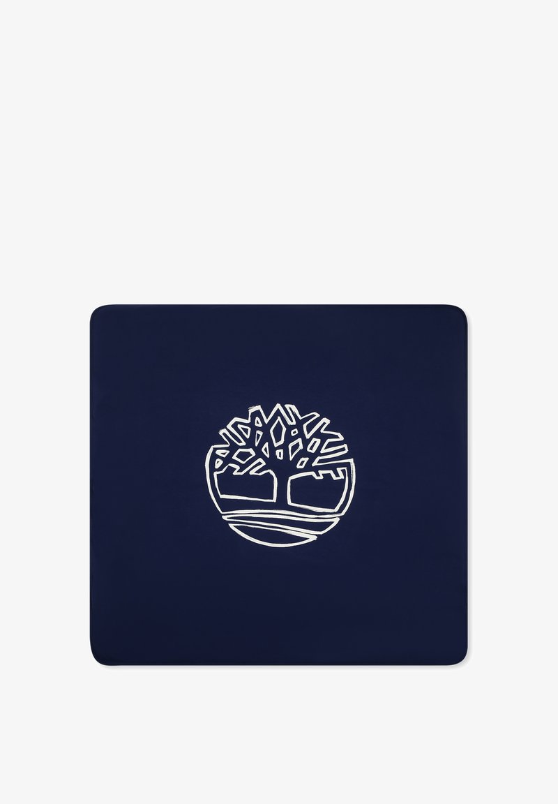 Tapis bleu marine arborant un logo blanc d'un arbre dans un cercle, avec des branches et des racines stylisées. Texture lisse et durable.