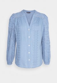 Blouse bleu clair à manches longues avec boutons blancs, motifs en dentelle à jours et poignets froncés.