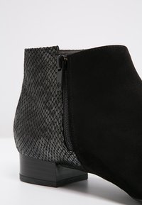 Bottine noire à la cheville avec un dos texturé motif serpent et un avant en suédine lisse, avec une fermeture éclair latérale et un petit talon bloc.