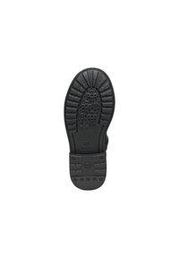 Semelle de chaussure en caoutchouc noir présentant une adhérence texturée avec des motifs circulaires et croisés, un bord incurvé au talon, et des détails de marque en relief.