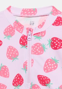 Μπλούζα χωρίς μανίκια της Baby GAP με ροζ και κόκκινα φραουλένια σχέδια και φερμουάρ μπροστά σε ανοιχτό μωβ ύφασμα.