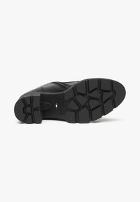 Black boot sole with a rugged tread pattern, featuring a firm rubber material and flat profile. Includes logo detail and textured accents.