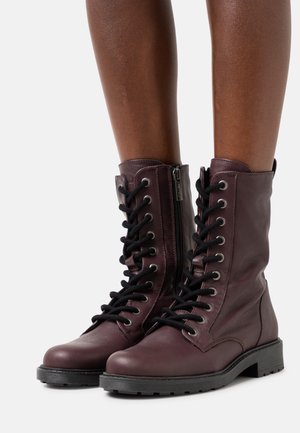 Bordeaux læder ankelstøvler med sorte snørebånd, sidezipper, rund tå og struktureret gummisål. Har metaløjer og syede detaljer.