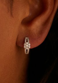 Zilveren oorringen met een bloemenmotief, versierd met meerdere kleine, helder gekleurde edelstenen, met een gladde, gepolijste afwerking.