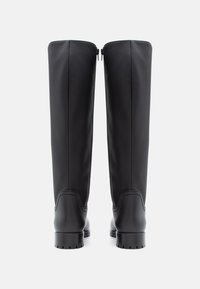 Črne gležnjarje do kolen, izdelane iz gladkega materiala, z zaobljenim nosom, teksturiranimi detajli na podplatu in celotnim zadrgo na hrbtu.