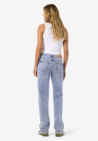 Απαλή μ�πλε τζιν παντελόνι με χαλαρή εφαρμογή, πέντε τσέπες και διακριτικά νευρώματα. Συνδυασμένο με λευκή ριμπ μπλούζα χωρίς μανίκια.