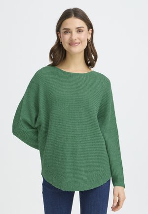 Grüner, locker sitzender Pullover aus strukturiertem Strickmaterial mit einem Bootsausschnitt und zulaufenden Ärmeln, kombiniert mit Jeans.