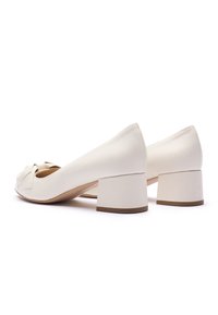 Vita blockklackade skor i läder med rundad tå och rosett detalj framtill. Klacken är i en solid, kontrasterande färg för stabilitet.