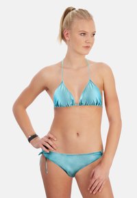 Ensemble de bikini à pois turquoise comprenant un haut triangulaire avec des bords froncés et des liens ajustables en bas, fabriqué à partir d'un tissu brillant.