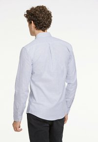 Męska koszula z długim rękawem w jasnoniebieskie i białe paski, wykonana z bawełny. Posiada kołnierzyk zapinany na guzik oraz mankiety, z zaokrąglonym dołem.