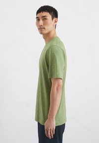 Green striped t-shirt in soft fabric, short sleeves, crew neck, and a relaxed fit, displayed against a plain white background.