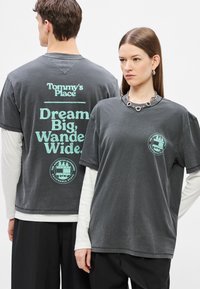 Μπλουζάκι από βαμβάκι σε ανθρακί γκρι με άνετη εφαρμογή. Διαθέτει κείμενο στην πλάτη σε μέντα πράσινο, που περιλαμβάνει λογότυπο και σύνθημα. Μανίκια κοντά.