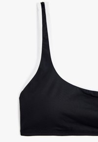 Top bikini nero con sottili spalline, rifinito con bordature bianche lungo i lati. Tessuto liscio ed elastico con cuciture unite per una maggiore durata.
