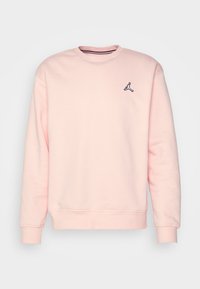 Sudadera rosa con cuello redondo, mangas largas y puños acanalados. Presenta un pequeño logo negro de Jordan en el pecho. Material suave.