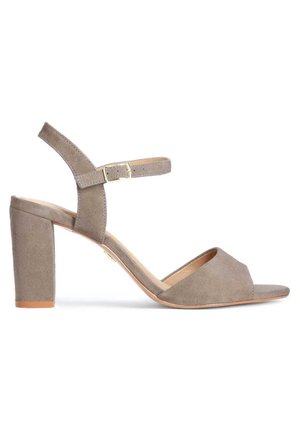Sandale à talon bloc en daim gris, avec bout ouvert, bride à la cheville avec boucle réglable et semelle intérieure en cuir lisse légèrement brillante.