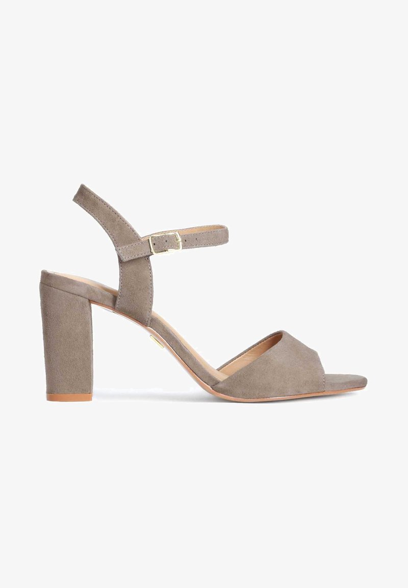 Sandale à talon bloc en daim gris, avec bout ouvert, bride à la cheville avec boucle réglable et semelle intérieure en cuir lisse légèrement brillante.