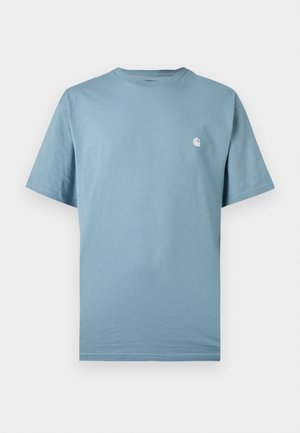 Camiseta azul claro de manga corta con cuello redondo y un pequeño logo blanco en el pecho izquierdo, mostrada sobre un fondo liso.