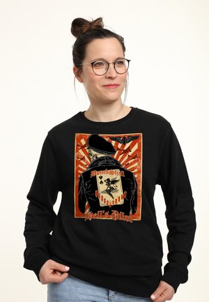 Czarny sweatshirt z grafiką pilota na plecach, z wyraźnym napisem "BombShell" i "Hell's Pilot", osadzonym na tle czerwonej eksplozji słonecznej.