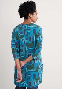 Blå och grönmönstrad tunika med trekvartslånga ärmar, som har abstrakta former och en avslappnad passform, tillverkad av ett mjukt material.