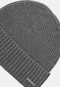 Szara dziana czapka typu beanie z prążkowaną teksturą, z podwiniętym mankietem. Na mankiecie znajduje się mała metka marki, co dodaje subtelnego akcentu.