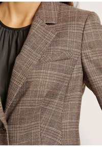 Braun karierter Blazer aus strukturiertem Stoff mit Reverskragen, zwei Knöpfen und dezenten orangen Akzenten im Muster.