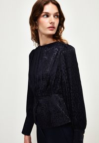Navybluse aus strukturierter Stoff mit einem dezenten Tiermuster, mit hohem Kragen, langen Ärmeln und Raffung am Bund.