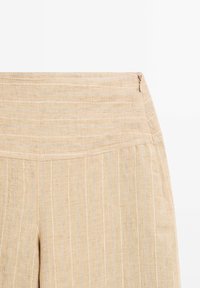 Pantaloni beige in lino con strisce verticali azzurro chiaro, caratterizzati da una cintura liscia e una chiusura a zip su un lato.