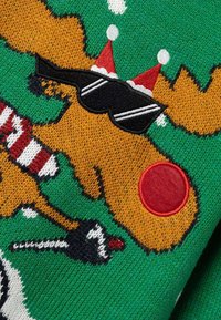 Pull en tricot vert avec un motif de renne festif. Comprend un nez rouge, des lunettes de soleil, une écharpe rayée rouge et blanche, et des accents de neige blanche.