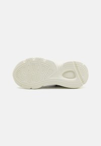 Suela de zapatilla en color blanco roto, con patrones y surcos texturizados para tracción, superficie lisa y un minimalismo en el branding.