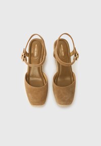 Πέδιλα τακουνιού σε ταμπά σουέτ με τετράγωνη μύτη, ρυθμιζόμενο λουράκι στον αστράγαλο και υφασμένο σόλα με πλατφόρμα. Εσωτερική σήμανση ορατή.